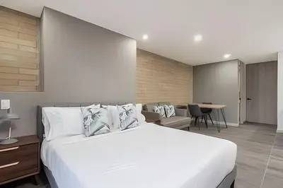 a bedroom with a large white bed and a table at Class 48 Apt. 2301 - Luces de ciudad/Loft/Balcón priv in Sabaneta