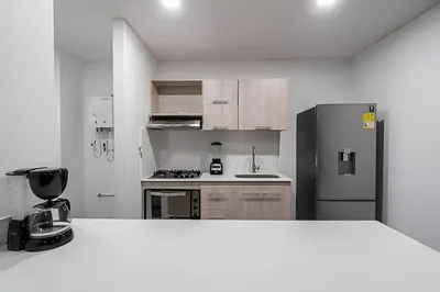 a white kitchen with a refrigerator and a stove at Class 48 Apt. 2301 - Luces de ciudad/Loft/Balcón priv in Sabaneta