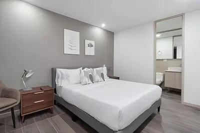 a bedroom with a large white bed and a chair at Class 48 Apt. 2303 - Loft de alta clase -balcón privado in Sabaneta
