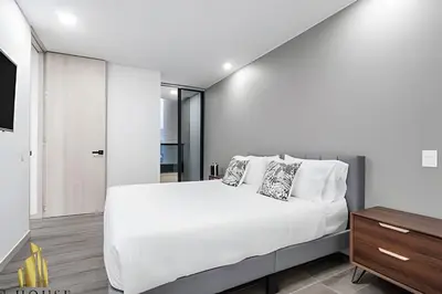 a white bedroom with a large bed and a tv at Class 48 Apt. 2304 - Apto con balcón privado/Sabaneta in Sabaneta