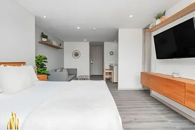 a bedroom with a white bed and a flat screen tv at Class 48 Apto. 2501 - Apto tranquilo y luminoso/balcón in Sabaneta