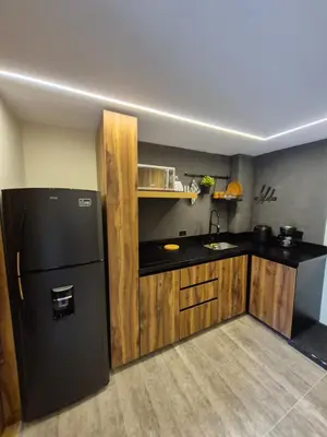 a kitchen with a black refrigerator and wooden cabinets at Mali Experience in Rionegro
