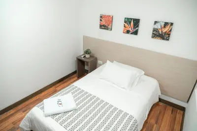 a bedroom with a white bed and a wooden floor at Hotel Quinta del Café in Fredonia