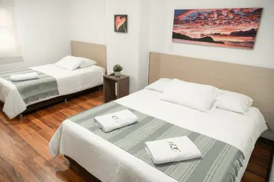 two beds in a hotel room with white sheets at Hotel Quinta del Café in Fredonia