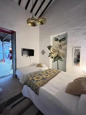 a bedroom with two beds and a flower on the wall at Hotel Art Boutique Las Cardenas in Carolina del Principe