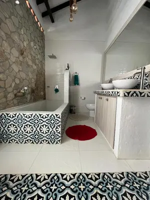 a bathroom with a tub and a sink and a red rug at Hotel Art Boutique Las Cardenas in Carolina del Principe