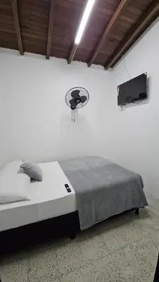 a bedroom with a bed and a tv on the wall at Hotel casa yotama in Medellín