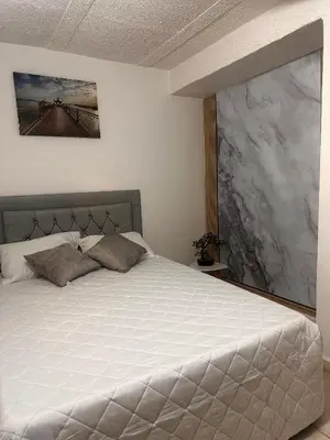 a bedroom with a white bed with a painting on the wall at Excelente Apartamento en Medellín sector Florida Nueva - Estadio in Medellín