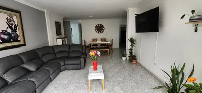 a living room with a couch and a table with flowers at EmiliasHome Alojamiento amplio en Laureles in Medellín
