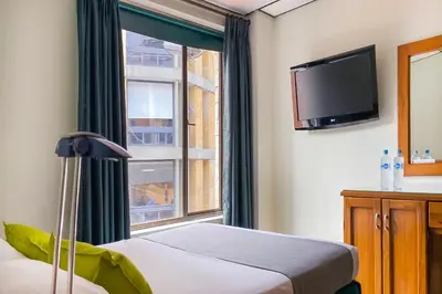 a bedroom with a bed and a tv and a window at Ayenda 1140 Roma Plaza in Manizales