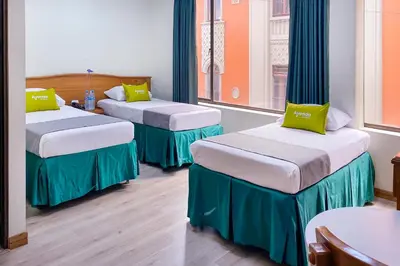two beds in a room with two windows at Ayenda 1140 Roma Plaza in Manizales