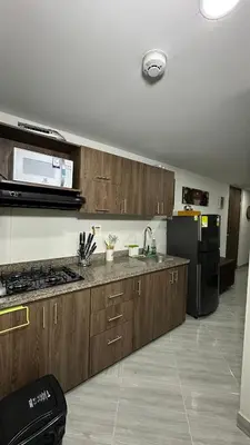 a kitchen with wooden cabinets and a black refrigerator at Apto estudio moderno en Sabaneta Ideal para pareja in Sabaneta