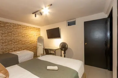 a bedroom with two beds and a brick wall at Hotel Garden Laureles in Medellín