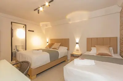 a hotel room with two beds and a mirror at Hotel Garden Laureles in Medellín