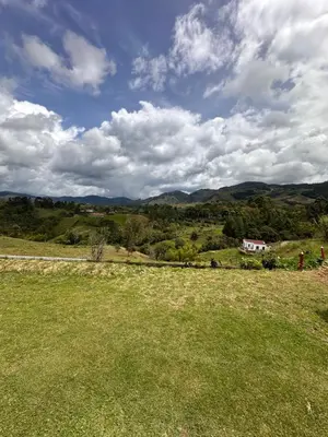 a field of grass with a house in the distance at Finca La Carolina in Jericó