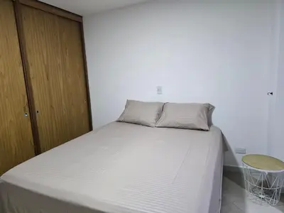 a white bed in a room with a wooden cabinet at EstadioMedellin in Medellín