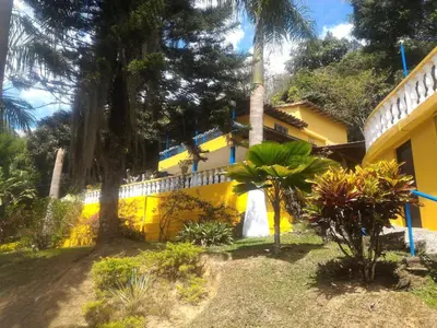 a yellow house with a white fence and trees at Finca Villa Palma in Barbosa