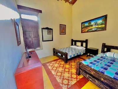 a room with two beds and a table and a window at Casa Real - Encanto Colonial in Sopetran