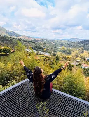 a woman sitting on a grate looking out over a valley at Cabaña con jacuzzi y vista al embalse - Ocasia in Chiquinquirá