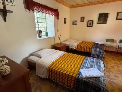 two beds in a room with a window at Casa de campo a 5 minutos from Sonsón in Sonsón