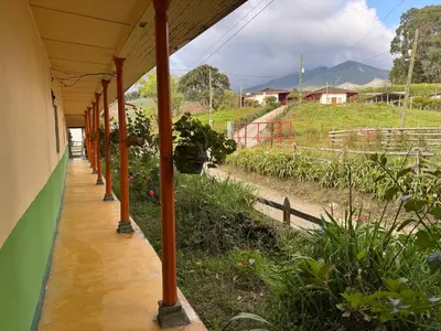 a building with a porch with a garden with plants at Casa de campo a 5 minutos from Sonsón in Sonsón