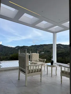a porch with two chairs and a table and a view at Villa de lujo con piscina, jacuzzi y vista maravillosa in El Peñol