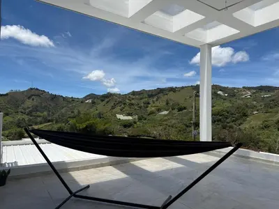 a hammock on a porch with a view of a mountain at Villa de lujo con piscina, jacuzzi y vista maravillosa in El Peñol
