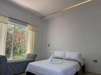 a bedroom with a bed and a couch and a window at Villa de lujo con piscina, jacuzzi y vista maravillosa in El Peñol