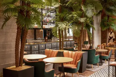 a restaurant with palm trees and tables and chairs at The Host Medellin Adults Only in Medellín