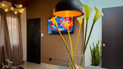 a vase with yellow flowers sitting on a table with a lamp at Urban Lofts Laureles 40 in Medellín