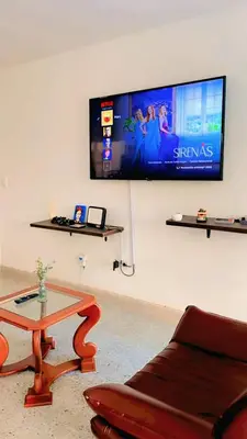 a living room with a couch and a table and a tv at Hostal Abba in Medellín