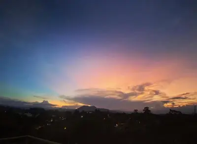 a sunset over a city with a cloudy sky at Alto Paraiso Glamping 