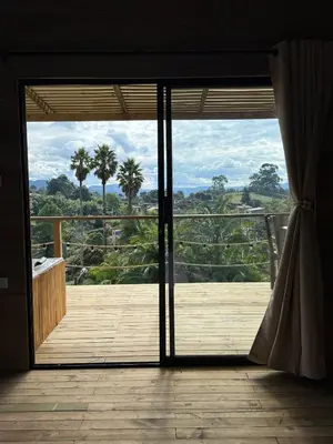 an open door to a deck with palm trees at Alto Paraiso Glamping 