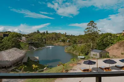 a view of a river with chairs and umbrellas at Okai by Bernalo Hotels in Guatapé