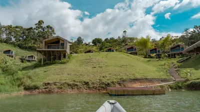 a resort on the river with a boat in the water at Okai by Bernalo Hotels in Guatapé