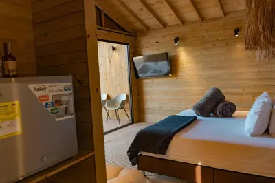 a small bedroom with a bed and a refrigerator at Okai by Bernalo Hotels in Guatapé
