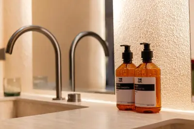 two bottles of soap sitting on a counter next to a sink at The Cut Hotel in Medellín