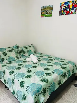 a bed in a room with a green and white comforter at Casa Almanik Hostel in Medellín