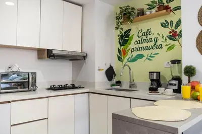 a kitchen with white cabinets and a green wall at Coffee Spring Studio Medellin in Medellín