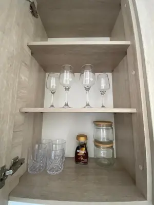 a row of wine glasses and jars on a shelf at calido y tranquilo apartamento in Sabaneta