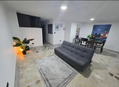 a living room with a black couch and a table at Acogedor apto laureles estadio in Medellín