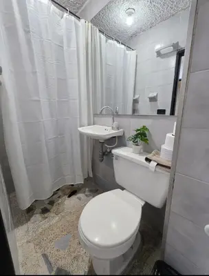a white bathroom with a toilet and a sink at Acogedor apto laureles estadio in Medellín
