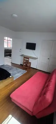 a living room with a red couch and a table at habitaciones amobladas la estrella in Manizales