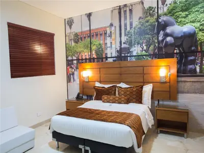 a bedroom with a large bed and a large mural at Hotel Dorado La 70 in Medellín