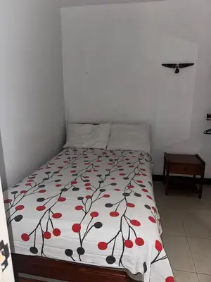 a bed in a bedroom with a bedspread with red flowers at Hotel Café de la Montaña in Pensilvania
