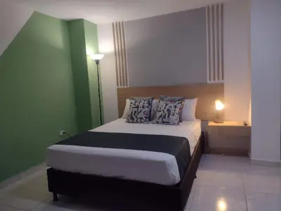 a bedroom with a large bed with green walls at 44-20 Tiny Loft in Medellín