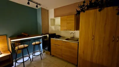 a kitchen with wooden cabinets and a sink and bar stools at 44-20 Tiny Loft in Medellín