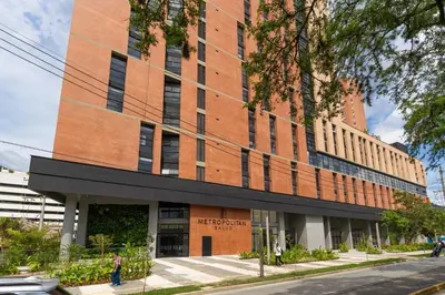 a red brick building with a person walking in front of it at Metropolitan Living by HOUSY in Medellín