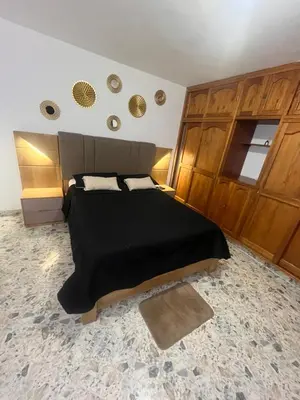a bedroom with a black bed and wooden cabinets at Amplio apartamento Guayabal cerca aeropuerto Olaya Herrera in Medellín