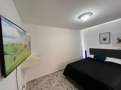 a bedroom with a bed and a flat screen tv at Amplio apartamento Guayabal cerca aeropuerto Olaya Herrera in Medellín